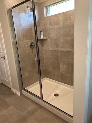 A contemporary walk-in shower with beige tile walls and a glass enclosure, offering a clean and sophisticated bathroom design.