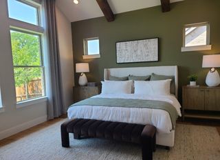 Model Home A cozy bedroom featuring a green accent wall, wooden beams, and elegant furnishings.