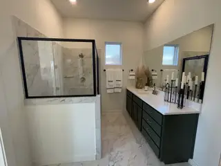 Model Home Modern bathroom with marble shower, sleek dark vanity, large mirror, and elegant decor accents.