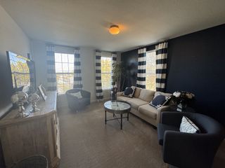 Model Home A cozy living room featuring a beige sofa, striped curtains, and elegant decor with ample natural light.