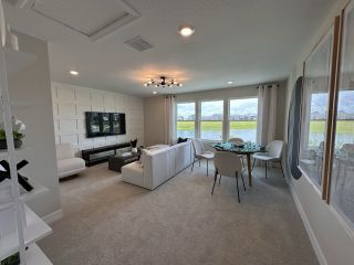 A modern living room with a chic sectional, stylish paneling, and large windows overlooking a scenic landscape.