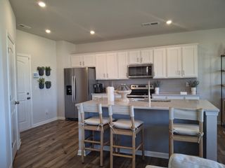 A modern kitchen featuring white cabinetry, stainless steel appliances, and a sleek island with barstool seating.