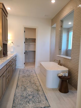 A luxurious bathroom featuring a freestanding tub, wood cabinetry, and elegant tile accents.