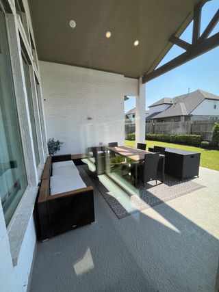 A cozy outdoor patio with wicker seating and a dining table under a modern, covered roof, perfect for relaxation.