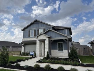 Elegant modern home featuring a blend of stone and wood accents, landscaped garden, and charming front porch in Riverbend at Double Eagle by Meritage Homes (Cedar Creek, TX).