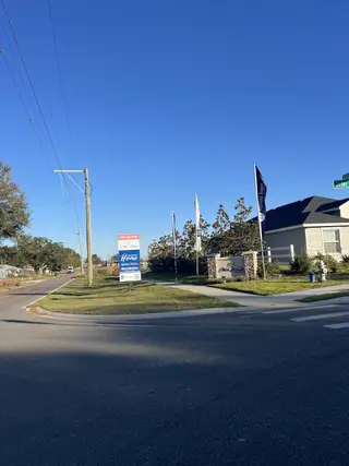 Entrance to Otter Woods Estates by Highland Homes of Florida, with flags and signage in Auburndale, FL.