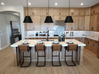 A modern kitchen with natural wood cabinets, black pendant lights, and a spacious island with stylish seating.