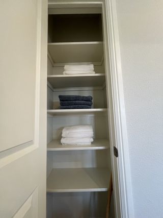 Model Home A neatly organized linen closet with white and navy towels on built-in shelves.