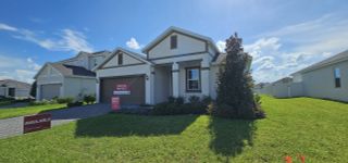 A charming modern home with a brown garage door, neutral siding, and lush landscaping in Leela Reserve by Park Square Residential (Tavares, FL).