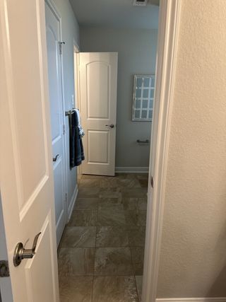 A bathroom with elegant beige tiles, soft lighting, and a stylish towel on a silver rack.
