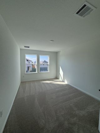 A spacious secondary bedroom with plush carpeting, large windows, and neutral walls, ready for personalization.