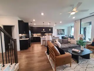 An open-concept living area with sleek black cabinets, cozy seating, and modern lighting, ideal for stylish entertaining.