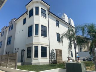 Street view A modern white townhouse with sleek windows and palm trees in Pelican View Townhomes by A-Team Petroleum Construction (Jacksonville Beach, FL).