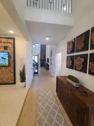 Model Home A modern hallway with wooden accents, a textured rug, and artistic wall decor, creating a warm and inviting atmosphere.