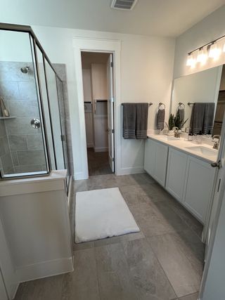 A bright and functional bathroom with a dual vanity, large walk-in shower, and neutral tile flooring.
