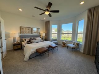 A spacious primary bedroom with large windows, neutral decor, and cozy seating, creating a relaxing retreat with natural light.