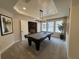 A chic game room featuring a pool table, modern lighting, cozy carpet, and stylish artwork for entertainment.