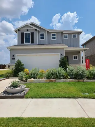 A charming gray two-story home with a landscaped yard in Ashford Crossing by Centex (Princeton, TX).