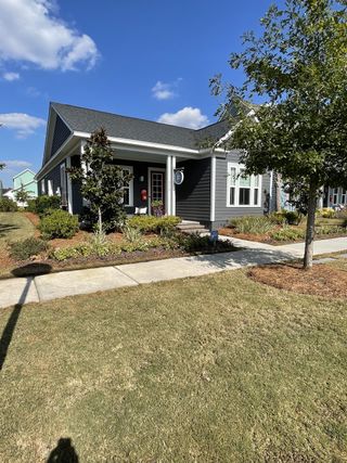 Charming gray home with a porch and lush landscaping in Midtown at Nexton by Ashton Woods (Summerville, SC).
