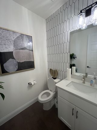 Model Home A modern bathroom with striking black hexagonal tile, a sleek vanity, and bright lighting.