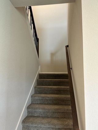 Model Home A modern staircase with carpeted steps and a sleek wooden handrail.