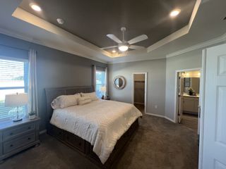 A spacious bedroom featuring a cozy king-sized bed, soft carpet, and tray ceiling with recessed lighting.