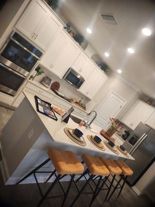 Model Home A chic kitchen with white cabinets, a modern island, and stylish bar stools, offering a perfect blend of function and style.
