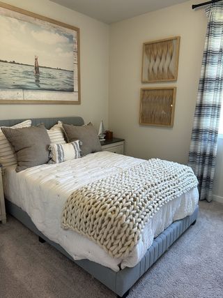 Cozy bedroom with textured decor, plush bedding, and serene artwork creating a relaxing atmosphere.