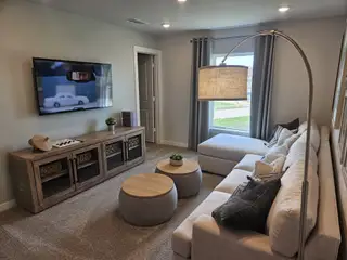 A cozy living room with a sectional sofa, modern TV setup, elegant lighting, and neutral decor for relaxation and entertainment.