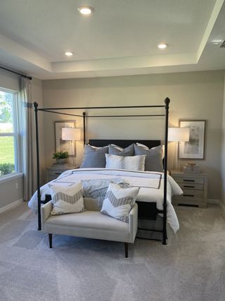 A cozy bedroom with a modern canopy bed, elegant lighting, and a soft carpet, creating a serene retreat.