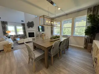 A spacious living and dining area with a cozy fireplace, modern decor, and large windows for natural light.