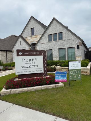 A charming gray brick home with vibrant landscaping in Harvest Green 45' by Perry Homes (Richmond, TX).