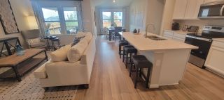 A spacious, open-concept living area in a Remington Ranch home, featuring a modern kitchen with a large island, a comfortable living room, and ample natural light (San Antonio, TX).