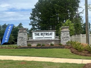 Charming entrance with stone pillars and lush greenery at The Retreat At Cameron Commons by Lennar (Charlotte, NC).