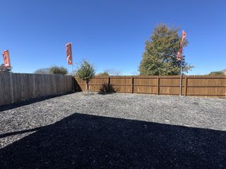 A spacious fenced yard with wooden planks and vibrant flags in Cloud Country by CastleRock Communities (New Braunfels, TX).