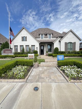 Street view A beautiful white brick home with a manicured garden in Devonshire by Highland Homes (Forney, TX).