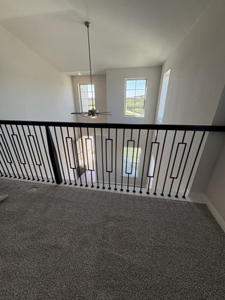A carpeted loft area with sleek iron railings and large windows flooding the space with natural light.