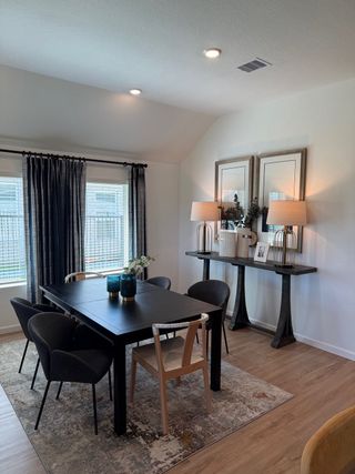 Model Home A modern dining area with a sleek black table, elegant chairs, and stylish decor, featuring warm lighting and cozy ambiance.