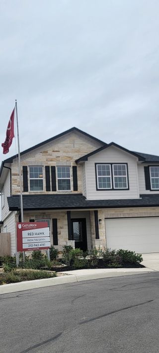 Street view A charming two-story home with stone accents and a manicured front yard in Red Hawk Landing by CastleRock Communities (San Antonio, TX).