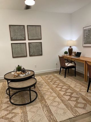 A modern home office with geometric wall art, cozy lighting, and a natural wood desk.