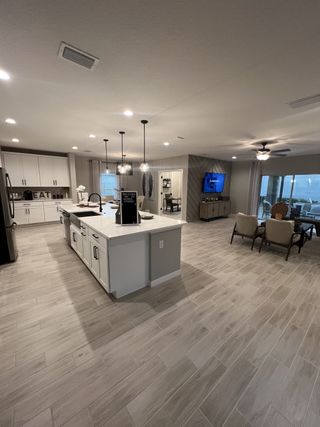 A spacious open-concept kitchen and living area with modern cabinetry, sleek flooring, and elegant lighting fixtures.
