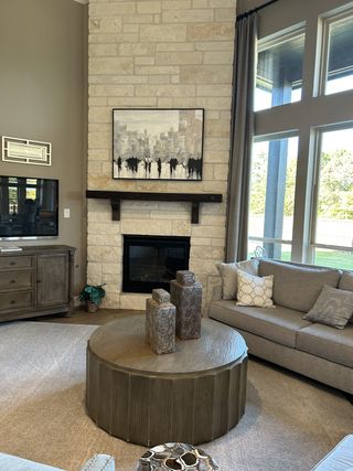 A cozy living room featuring a stone fireplace, round wooden table, and plush gray sofas with stylish décor accents.