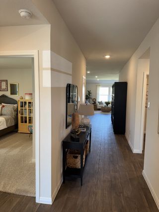 A welcoming hallway with wooden flooring, modern decor, and soft lighting leading to a bright living area.