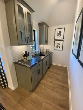Model Home A sleek wet bar with modern cabinetry, black countertop, and elegant wall art for a stylish touch.