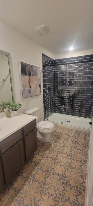 A chic bathroom with dark subway tiles, patterned flooring, and elegant decor for a modern touch.