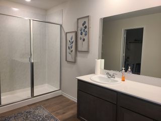 A modern bathroom featuring a glass-enclosed shower, sleek dark vanity, and decorative wall art.