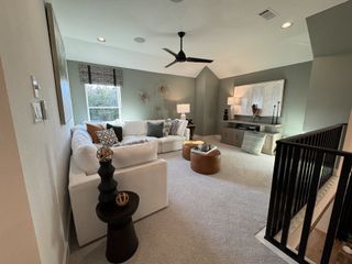 Model Home A cozy living area with a plush sectional, modern ceiling fan, and stylish decor in a neutral palette.