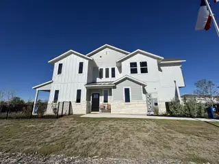 Street view A modern white home with stone accents and a neat lawn in Avery Centre by Landsea Homes (Round Rock, TX).