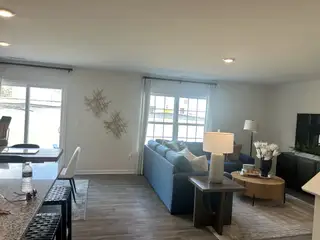 A cozy living room with a blue sectional, stylish decor, and natural light from large windows.