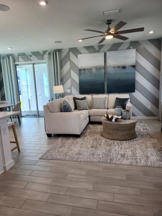 A cozy living room with a sectional sofa, abstract decor, chevron feature wall, and wood-tiled flooring.